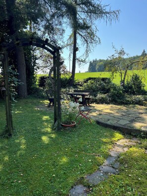 A garden with a wooden pergola, a stone bench, and a potted plant. - Stylish apartment with garden - newly renovated, quiet, ideal for families (Ottobeuren)