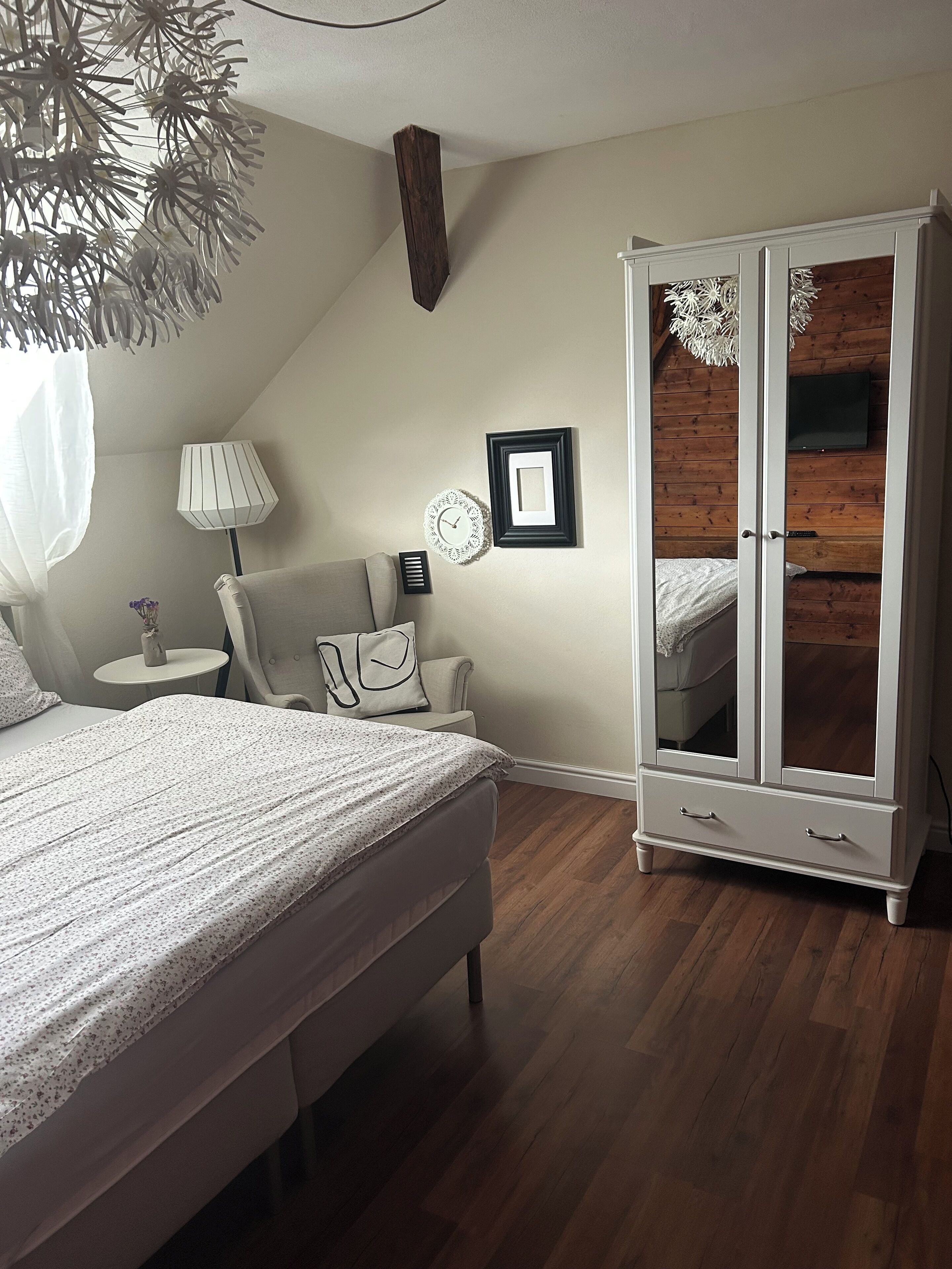 Une chambre à coucher comprenant un lit, une table de chevet, une lampe, une chaise, une armoire et un plafond en bois.