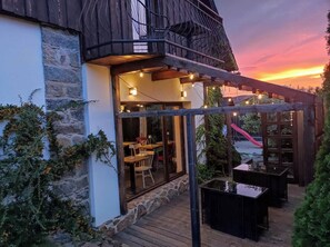 An outdoor patio area with stone walls, wooden tables, and chairs.