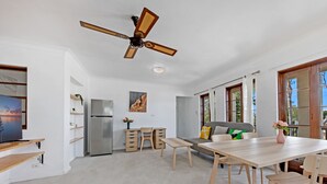 A modern kitchen with a built-in refrigerator, wooden cabinets, and a dining area with a table and chairs. - Kozyguru | Thornleigh | Townhouses (Thornleigh)