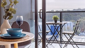 Un balcón con una mesa, sillas, un florero con planta y una copa de vino.