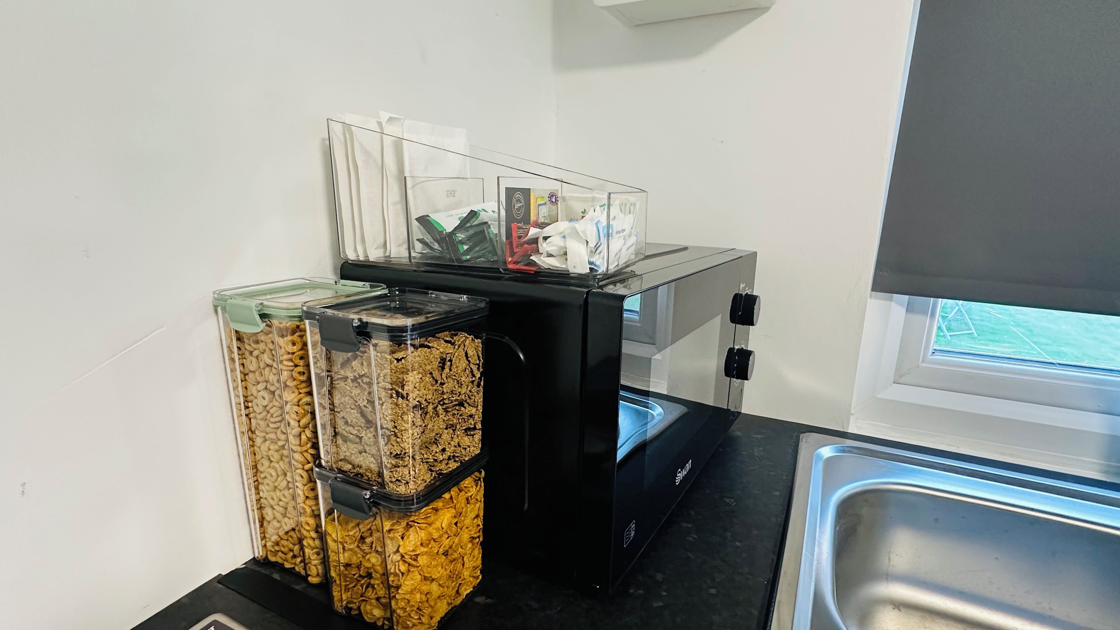 A kitchenette with a coffee machine, a trash bin, and a window with a view.