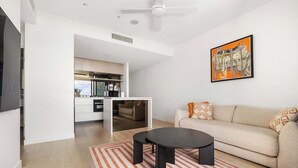 A modern living room with a sofa, a coffee table, and a kitchen area visible through an open door. - Queens Wharf Gem Stylish 1BR in BNEsNew Landmark (Brisbane City)