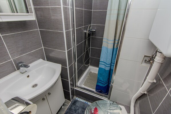 A bathroom with a white sink, a shower with a blue shower curtain, and tiled walls.