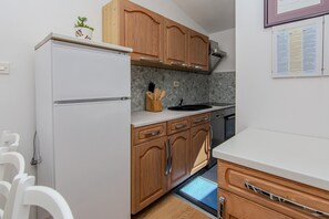 Una cocina compacta con armarios de madera, un refrigerador blanco, un lavamanos y una encimera.