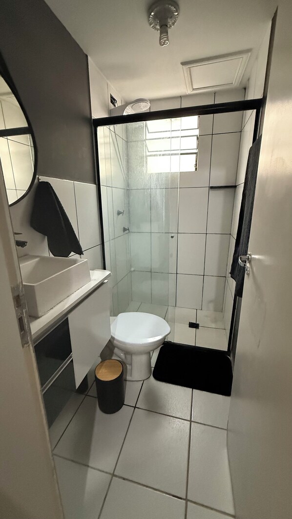 A compact bathroom with a toilet, sink, and shower.