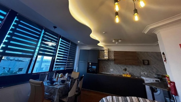 Una cucina moderna con soffitto curvo, elettrodomestici integrati e zona pranzo con tavolo e sedie.