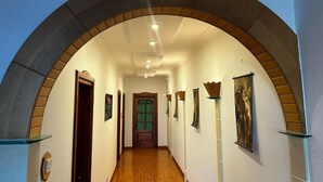 Un corridoio con un arco curvo, porte in legno e opere d'arte incorniciate alle pareti.