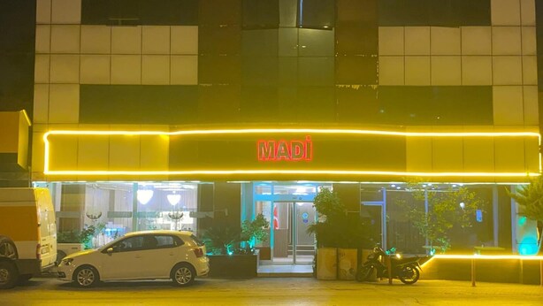 A hotel entrance with a neon sign reading "MADI" and a white car parked in front. - Adana Madi Hotel (Adana)