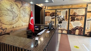 A reception desk with a world map mural, a red flag, and informational displays. - Adana Madi Hotel (Adana)