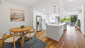 Una cocina moderna con una isla central, mesa de comedor de madera e iluminación empotrada.