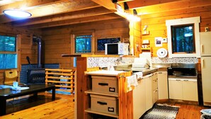 A wooden cabin interior with a kitchen area, wooden flooring, a fireplace, and a window overlooking the forest. - Private Log Cabin-Perfect for families, large groups, Parties are welcome! (Nasu-gun Nasu-machi)
