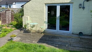 A small, single-story house with a white exterior and a large sliding glass door.