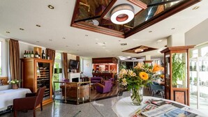 A spacious hotel lobby with a seating area, a bar, and a view of the city. - Hotel-Residenz-Leipzig (Leipzig)