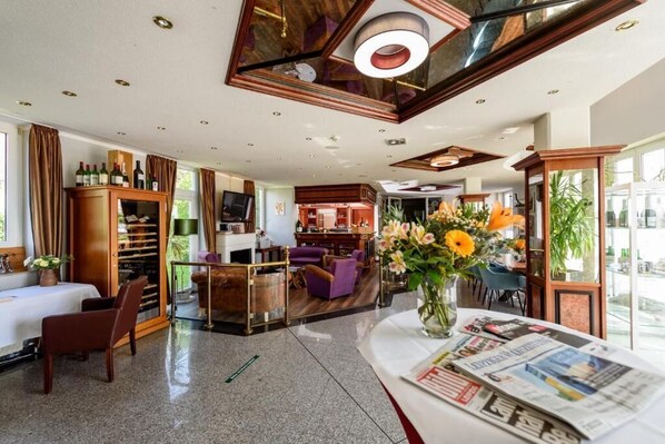 A spacious hotel lobby with a seating area, a bar, and a view of the city. - Hotel-Residenz-Leipzig (Leipzig)