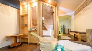 Una sauna con pareti in legno, una panca di legno, un tavolo con una bacinella e un asciugamano, e un piccolo ripiano con degli oggetti.