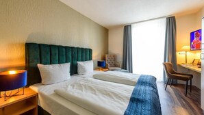 Una camera d'albergo con due letti, una scrivania, una sedia e una televisione.