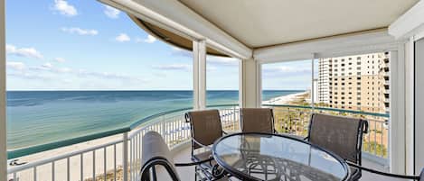 Ein Balkon mit Glastisch und Stühlen mit Blick auf Strand und Meer.