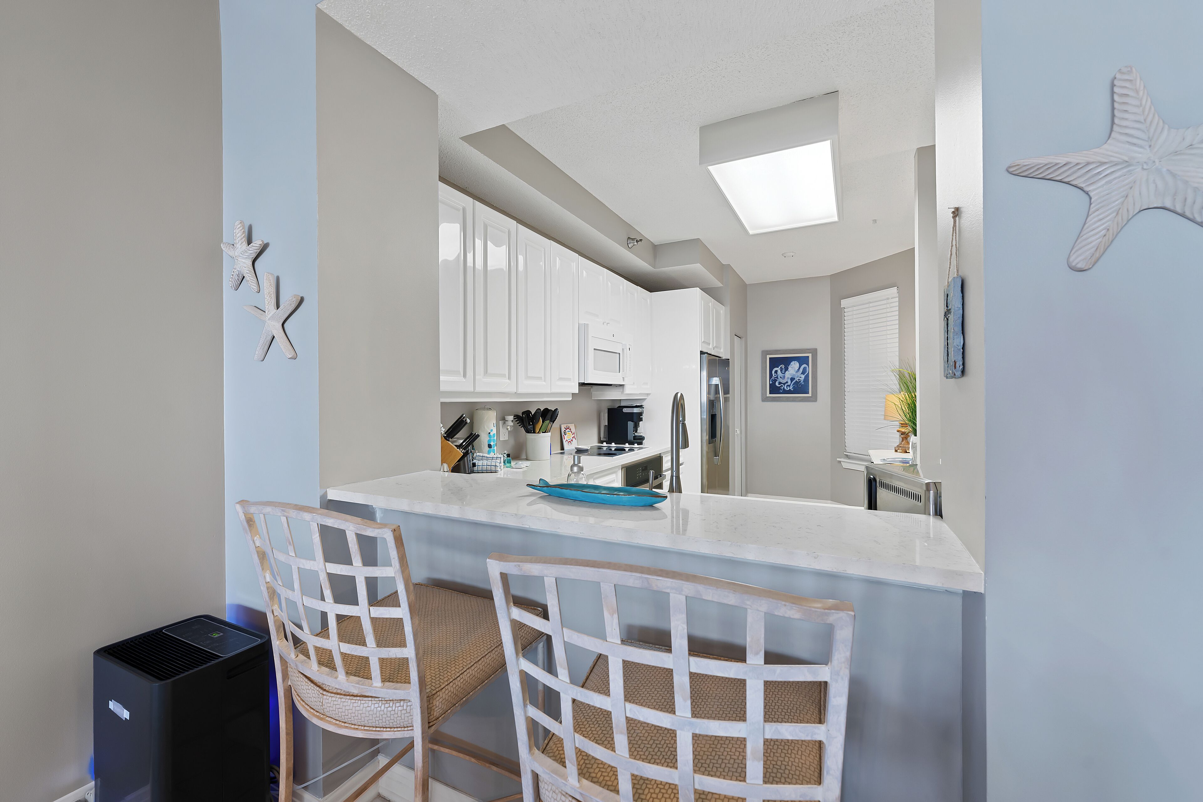 A modern kitchen with white cabinets, a central island, and a starfish decoration.