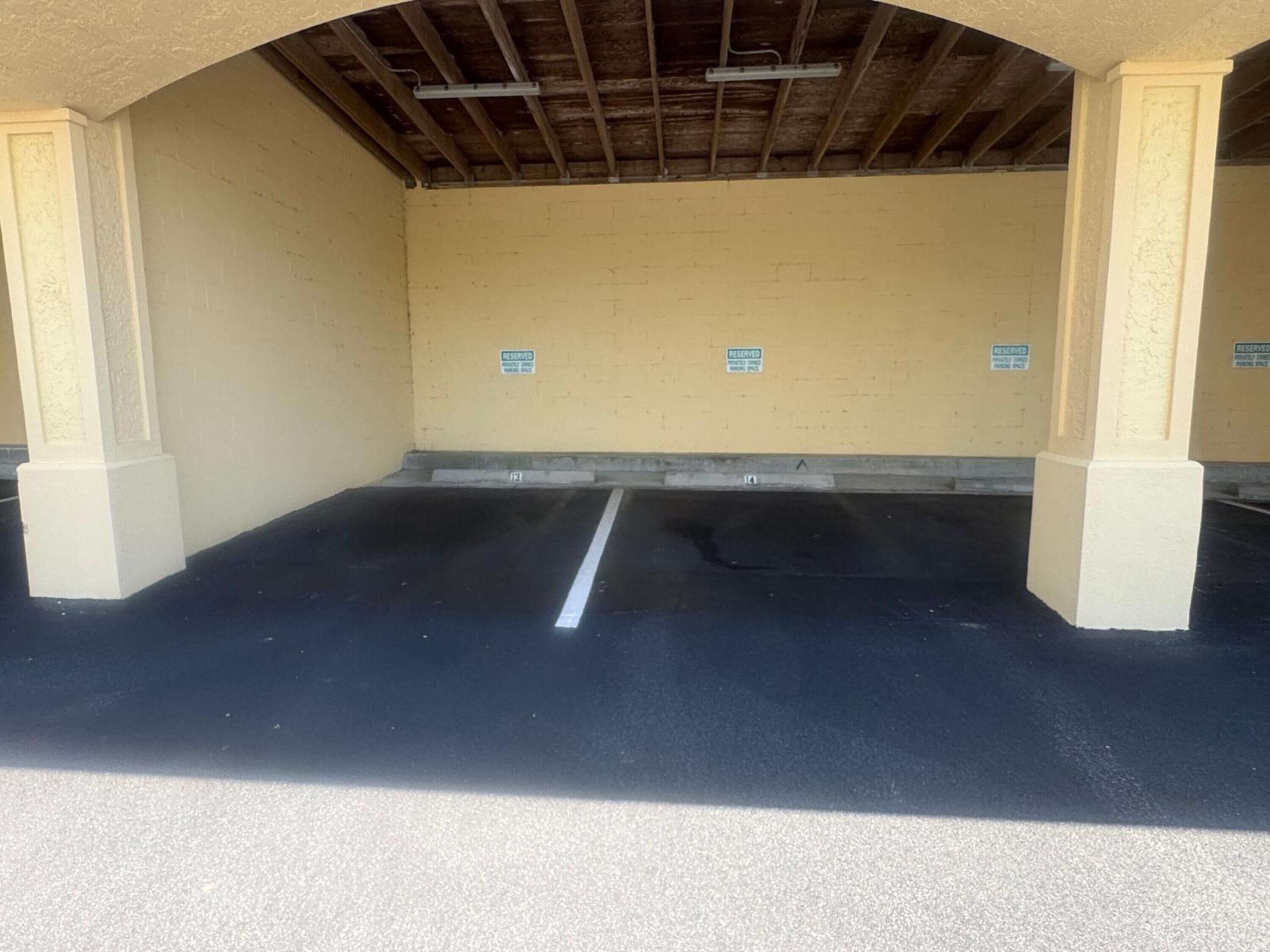 An empty parking garage with reserved signs on the walls and a clear path marked on the floor.