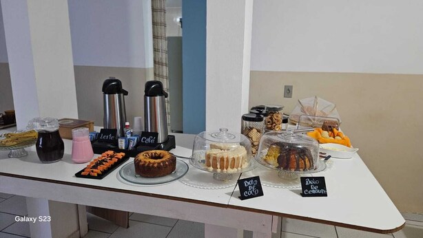 A buffet table with various food items and beverages, including cakes, pastries, and a coffee station. - Aroma hotel (Imbaú)