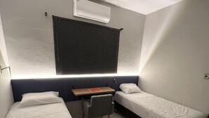 A small, modern room with two single beds, a desk, and a chair. - Aroma hotel (Imbaú)
