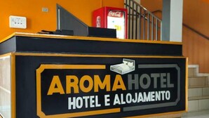 A reception desk with a Coca-Cola vending machine and a bed icon, indicating a hotel setting. - Aroma hotel (Imbaú)