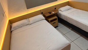 A hotel room with two single beds, a ceiling-mounted air conditioner, and a bedside table with a lamp. - Aroma hotel (Imbaú)