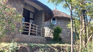 A stone house with a thatched roof, a wooden balcony, and a stone wall.