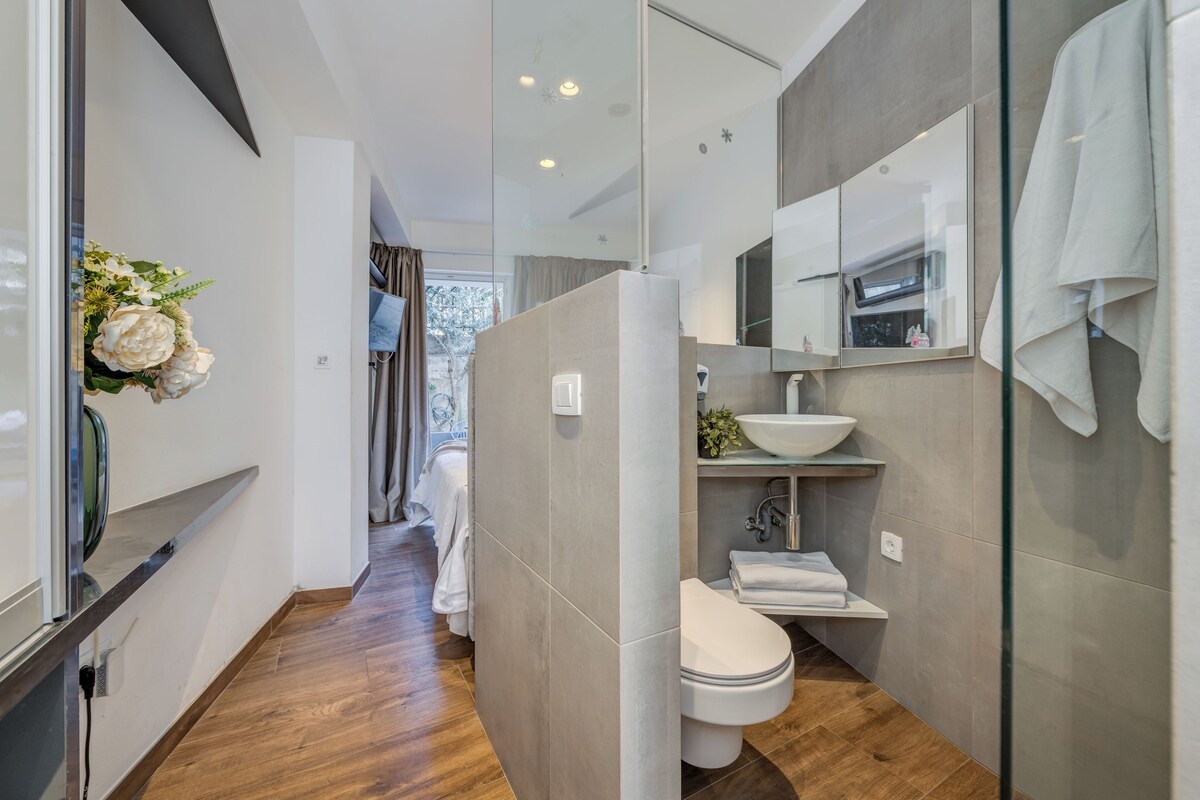 A modern bathroom with a glass shower enclosure, a white sink, and a toilet.