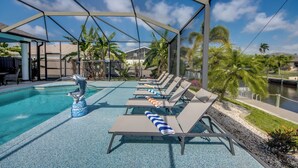 A pool area with lounge chairs and a dolphin statue. - Cape Coral Luxury Waterfront- Direct Gulf Access- Htd Pool- Bikes-5BDR -Villa 12 (Cape Coral)