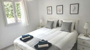 A bedroom with a bed, bedside tables, a ceiling fan, and framed pictures on the wall.