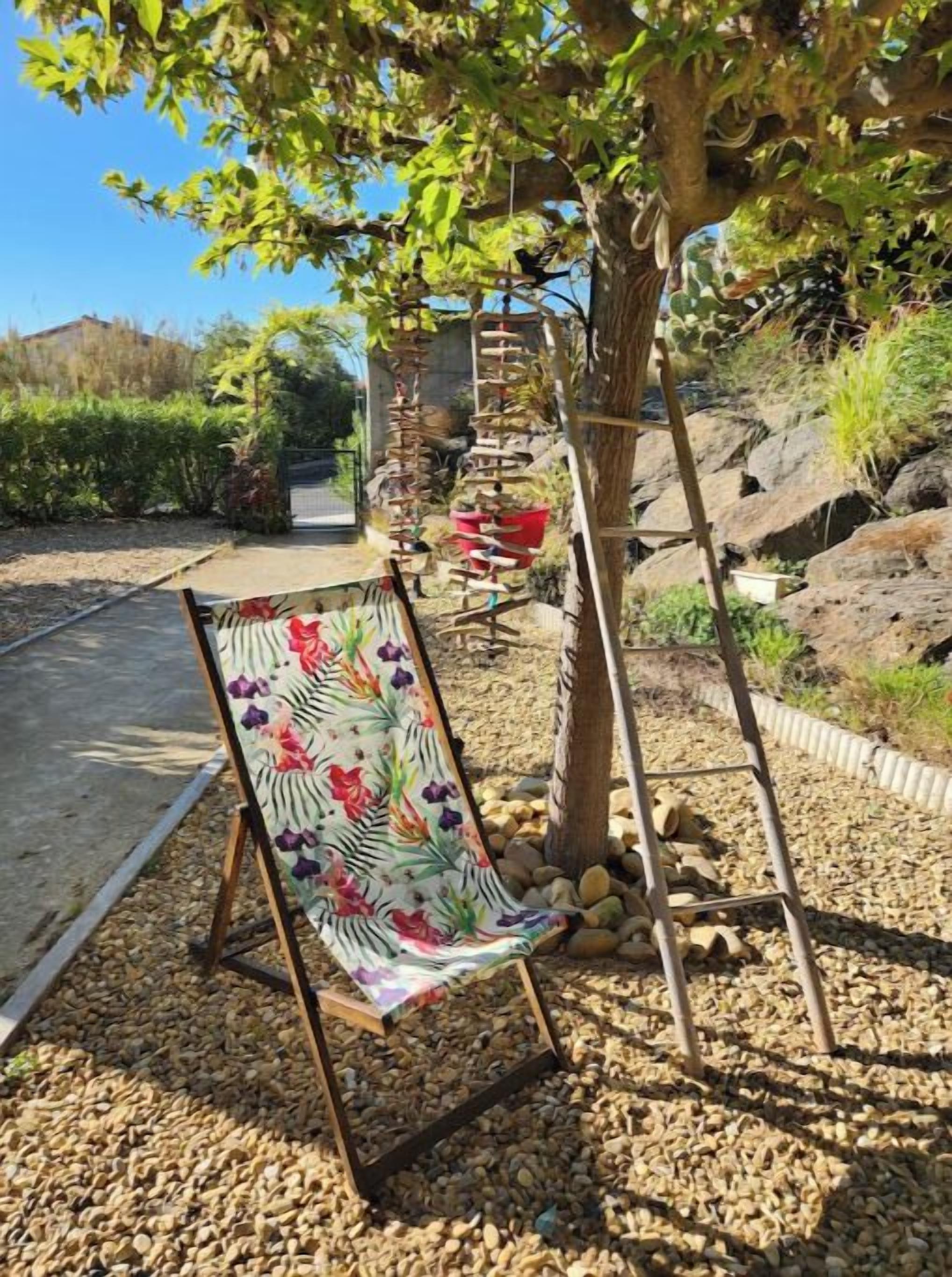 A garden with a wooden swing set, a ladder, and a decorative chair with a floral pattern.