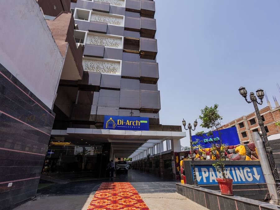 Entrada de un hotel con un letrero azul que dice "Di-Arch Hotel Lucena" y una alfombra roja que conduce al área de estacionamiento.