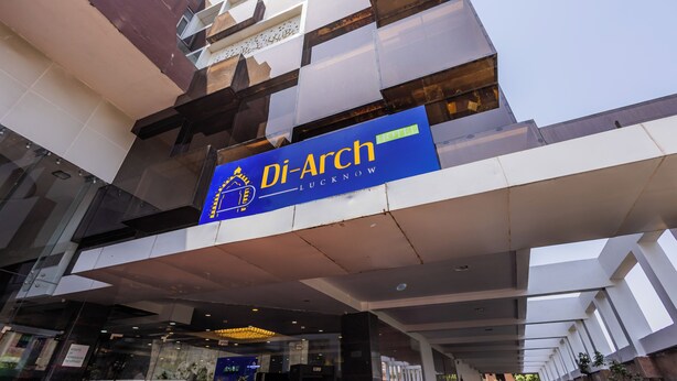 Exterior del Hotel Di-Arch con un llamativo letrero azul, arquitectura moderna y cielo despejado.