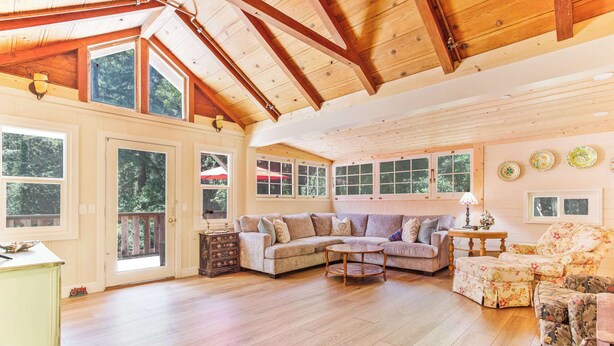 Amplia sala de estar con techo de madera, ventanas grandes y sofá modular.