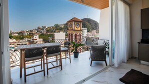 Uma varanda com vista para uma cidade, um campanário e um ventilador de teto.