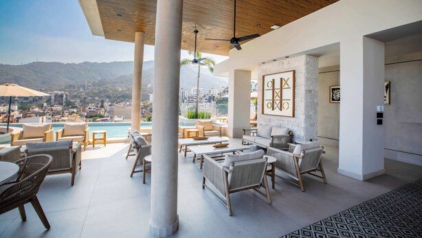 Um lounge no terraço com área de estar ao ar livre, piscina e vista para a cidade.