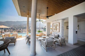Um lounge no terraço com área de estar ao ar livre, piscina e vista para a cidade.