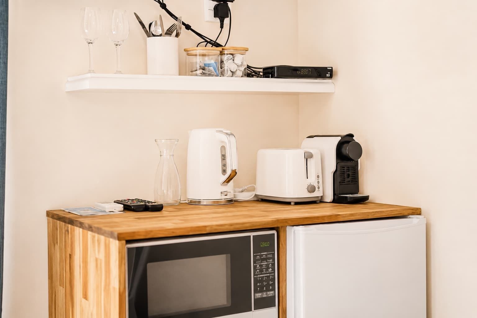 Eine Küchenzeile mit Mikrowelle, Toaster, Kaffeemaschine und einem kleinen Kühlschrank.