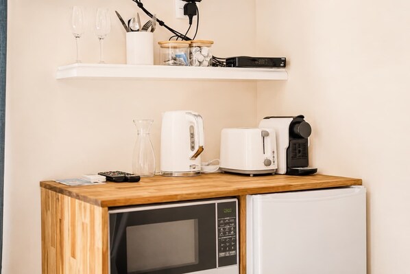 Una kitchenette equipada con microondas, tostadora, cafetera y un refrigerador pequeño.