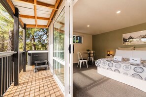 Ein Zimmer mit Bett, Schreibtisch und Stuhl, ein Balkon mit Grillmöglichkeit und Blick auf Bäume.