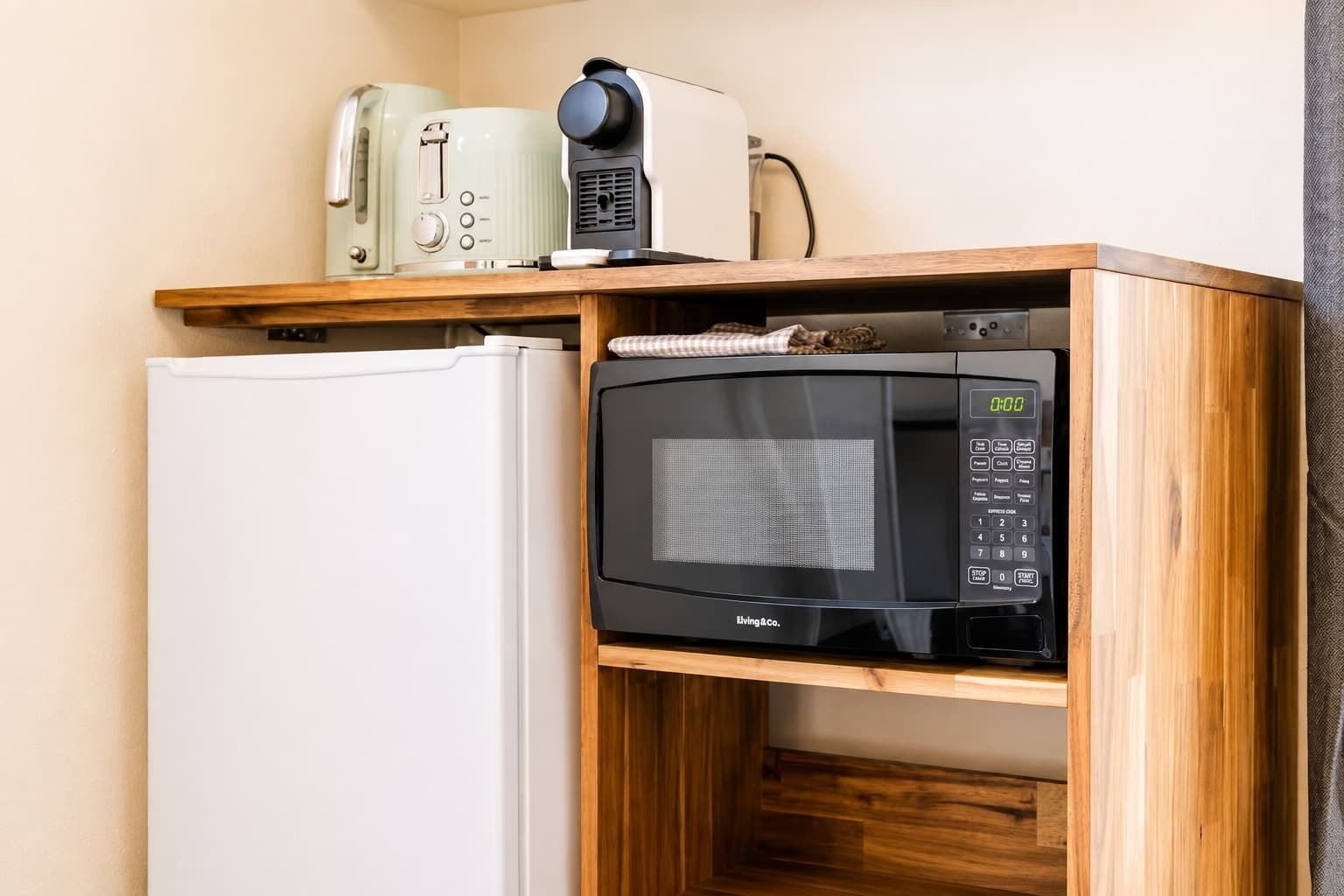 Eine kleine Küchenzeile mit einer Mikrowelle, einem Toaster und einem weißen Kühlschrank.