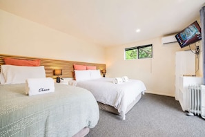 Habitación de hotel con dos camas, un televisor y una ventana.