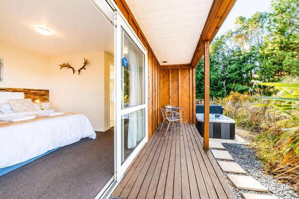 Habitaci ón de hotel con cama, escritorio y puerta corrediza de vidrio que da a una terraza al aire libre.