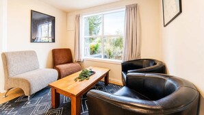 A room with a sofa, a chair, a table, and a window with curtains.