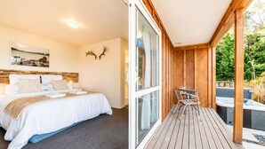A bedroom with a bed, a bedside table, and a window. - Orion | Lake Tekapo | Hot Tub | Sleeps 3 (Lake Tekapo)