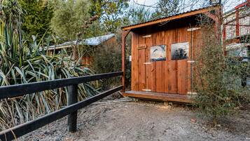 A wooden cabin with a black metal fence in front, surrounded by vegetation.