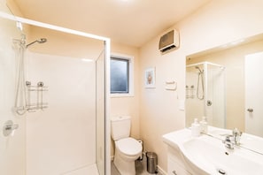 Ein Badezimmer mit Dusche, Toilette, Waschbecken und einem Fenster.