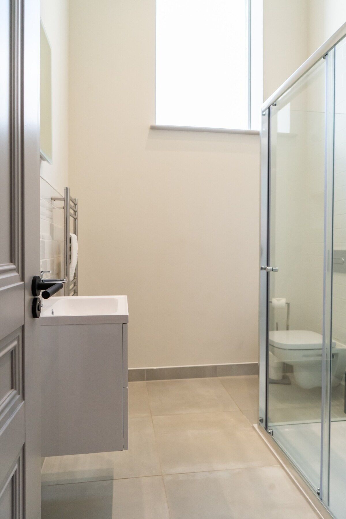 A bathroom with a glass shower enclosure, a white sink, and a toilet.